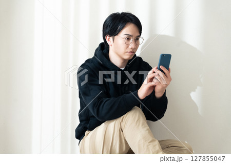 壁際でスマホを見る 127855047