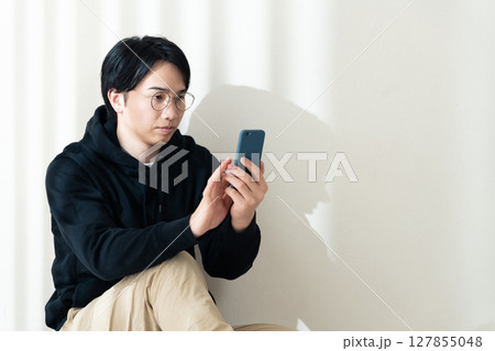 壁際でスマホを見る 127855048