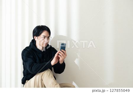 壁際でスマホを見る 127855049