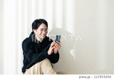 壁際でスマホを見る 127855050