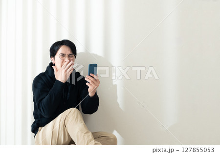 壁際でスマホを見る 127855053