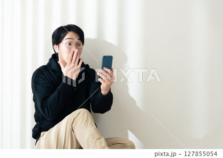 壁際でスマホを見る 壁際でスマホを見る 127855054