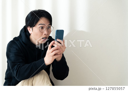 壁際でスマホを見る 127855057