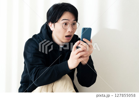 壁際でスマホを見る 127855058