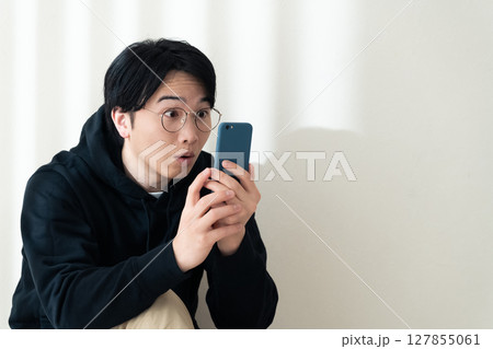 壁際でスマホを見る 127855061