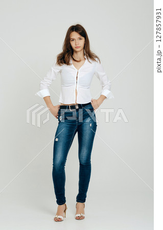 Teenager in a stylish outfit standing confidently against a neutral backdrop 127857931