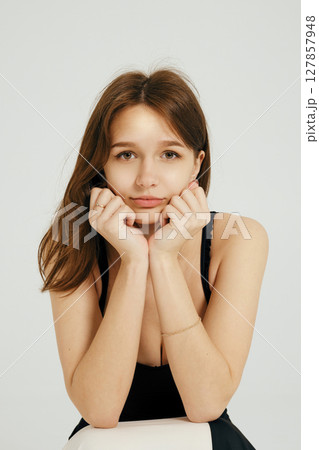 Teenager posing thoughtfully against a plain backdrop, expressing introspective emotions and style 127857948
