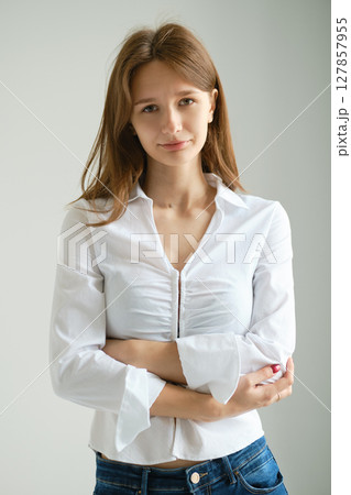 Teenager with long hair poses confidently in a stylish outfit indoors against a neutral background Teenager with long hair poses confidently in a stylish outfit indoors against a neutral background 127857955