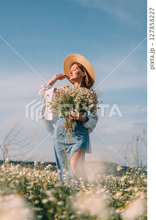 Daisies Woman Hat: Summer woman holds flowers in sunny field, enjoying nature's beauty. 127858227