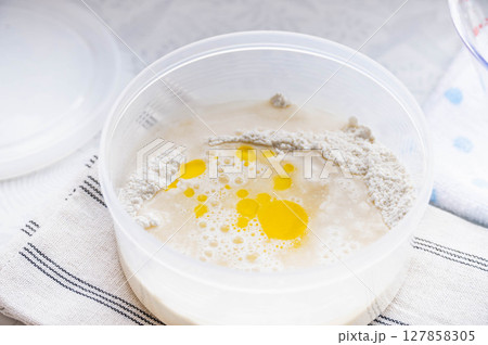 高加水パンの生地に水とオリーブオイルを加える 127858305