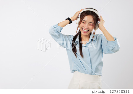Music in headphones lifts the mood of this smiling young Asian woman, listening as music flows with her lifestyle and joyful emotions. isolated studio white background Music in headphones lifts the mood of this smiling young Asian woman, listening as music flows with her lifestyle and joyful emotions. isolated studio white background 127858531