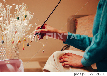 Colourful painted Easter eggs with a paint brush in a woman's hand. Authentic preparing decorations for the spring holidays in April. Home decor. 127859364