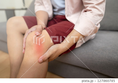 Man sitting on the couch and suffering from knee pain at home. Healthcare concept 127860785