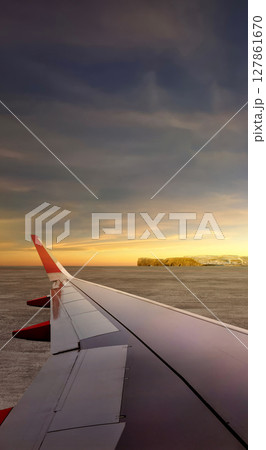 Airplane wing speeding on runway at takeoff with a landscape view of a sunset scene. Summer background 127861670