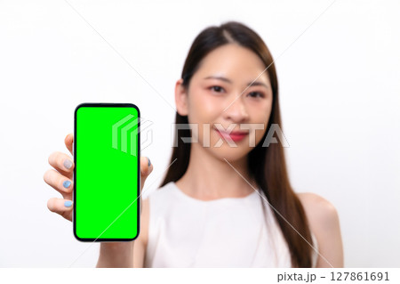 A beautiful Asian businesswoman shows a blank screen of mobile phone. She smiles at the camera A beautiful Asian businesswoman shows a blank screen of mobile phone. She smiles at the camera 127861691