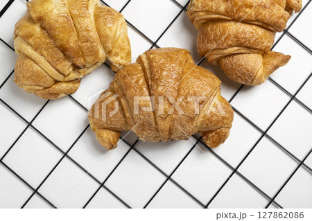 Freshly baked croissants on a cooling tray with a white background. Top view 127862086