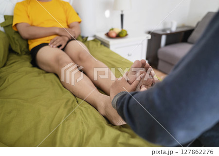 Woman massages her husband feet in the bedroom. Self-care and wellness routines concept 127862276