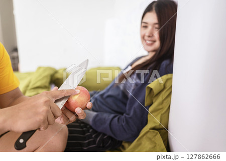 Man serving fruits to his Indonesian southeast asian wife in the bedroom in the morning. Healthy eating concept Man serving fruits to his Indonesian southeast asian wife in the bedroom in the morning. Healthy eating concept 127862666