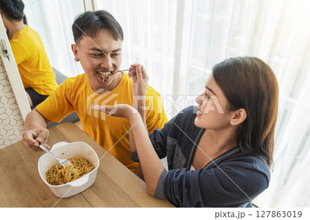 Indonesian southeast asian couple family eating noodles meal together in the dining room Indonesian southeast asian couple family eating noodles meal together in the dining room 127863019