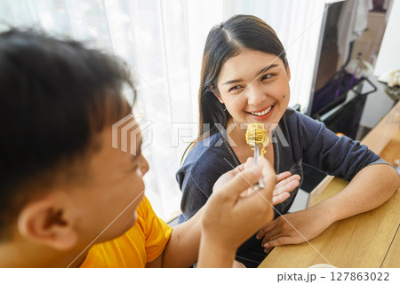Indonesian southeast asian couple family eating noodles meal together in the dining room 127863022