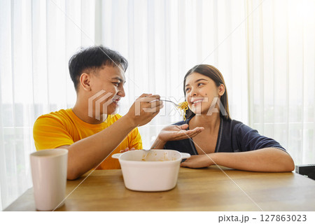 Indonesian southeast asian couple family eating noodles meal together in the dining room Indonesian southeast asian couple family eating noodles meal together in the dining room 127863023