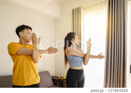 Indonesian southeast asian couple stretching before a workout at home for a healthy lifestyle and body care. Fitness and active lifestyles concept 127863028