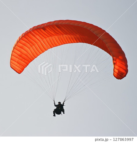 Paraglider with a red wing in the sky 127863997
