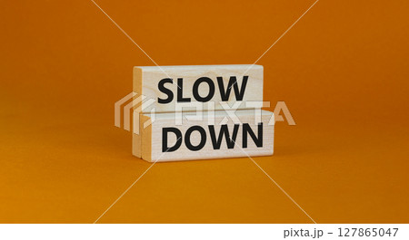 Time to slow down symbol. Concept words Slow down on wooden blocks on a beautiful orange background. Business and slow down concept. Copy space. 127865047