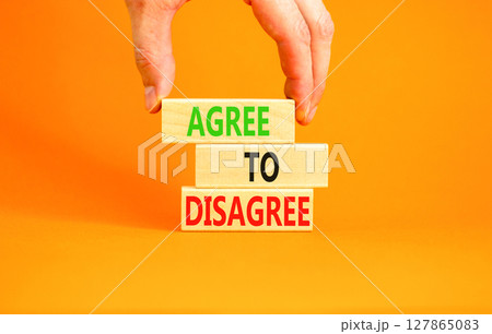 Agree to disagree symbol. Concept words Agree to disagree on beautiful wooden block. Businessman's hand. Beautiful orange background. Business and agree to disagree concept. Copy space. 127865083