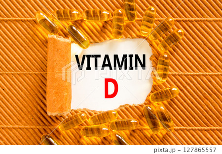Vitamin D symbol. Concept words Vitamin D on beautiful white paper. Yellow pills tablets. Beautiful brown background. Medical healthy lifestyle Vitamin D concept. 127865557