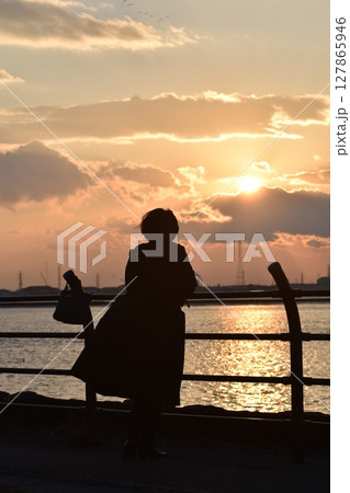 夕暮れ時に飛んでいく渡り鳥を見つめながら藤前干潟で黄昏る 夕暮れ時に飛んでいく渡り鳥を見つめながら藤前干潟で黄昏る 127865946
