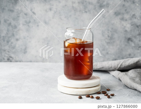 Cold brew coffee in a glass with ice on a marble stand on a light concrete background Cold brew coffee in a glass with ice on a marble stand on a light concrete background 127866080