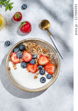 Natural greek yogurt with granola, blueberry and strawberry in a bowl on a light background Natural greek yogurt with granola, blueberry and strawberry in a bowl on a light background 127866091