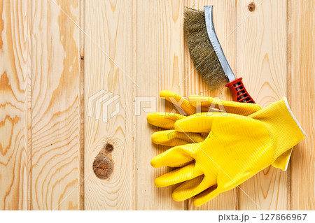 Yellow gloves and wire brush on wooden surface 127866967