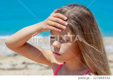 Caucasian child of 8 9 years holding hand on forehead feeling headache because of heatstroke on sea beach Caucasian child of 8 9 years holding hand on forehead feeling headache because of heatstroke on sea beach 127868332