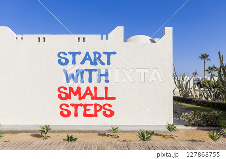 Start with small steps symbol. Concept words phrase Start with small steps on beautiful white wall. Beautiful white wall and blue sky background. Business Start with small steps concept. Copy space. 127868755