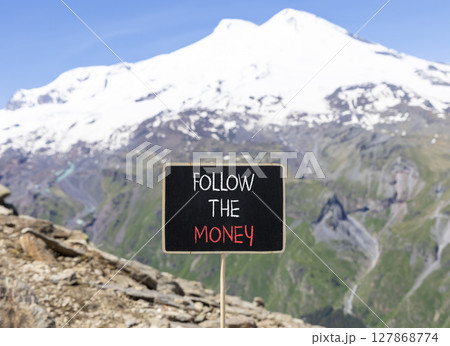 Follow the money symbol. Concept words Follow the money on beautiful black chalk blackboard. Beautiful mountain Elbrus background. Business and follow the money concept. Copy space. 127868774