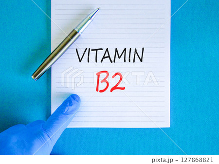 Vitamin B2 riboflavin symbol. Concept words Vitamin B2 on beautiful white note. Doctor's hand in blue medical glove. Beautiful blue background. Medical healthy lifestyle Vitamin B2 riboflavin concept. Vitamin B2 riboflavin symbol. Concept words Vitamin B2 on beautiful white note. Doctor's hand in blue medical glove. Beautiful blue background. Medical healthy lifestyle Vitamin B2 riboflavin concept. 127868821