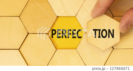 Perfection symbol. Concept word Perfection on beautiful wooden puzzles. Beautiful yellow background. Businessman hand. Business perfection concept. Copy space. 127868871
