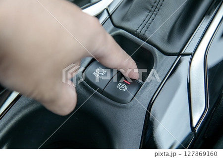 自動車の電動パーキングブレーキをオンにしている手 自動車の電動パーキングブレーキをオンにしている手 127869160