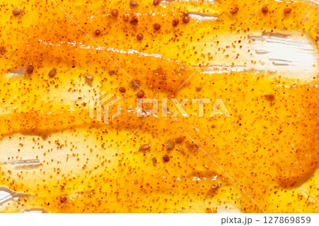 Vibrant close up of yellow mustard with red spices on a white background Vibrant close up of yellow mustard with red spices on a white background 127869859