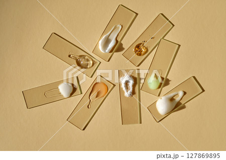 Samples of multi-colored cosmetic products on a beige background. 127869895