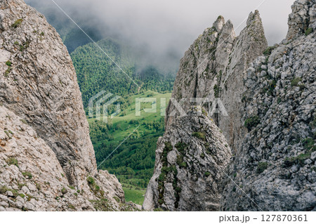Rocky mountain ridge and cliffs rising above clouds on a moody summer day. Bolshoy Tkhach national park Rocky mountain ridge and cliffs rising above clouds on a moody summer day. Bolshoy Tkhach national park 127870361