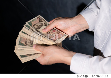 お金を持つ作業服の男性 127870953