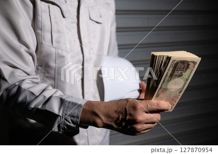 お金を持つ作業服の男性 お金を持つ作業服の男性 127870954
