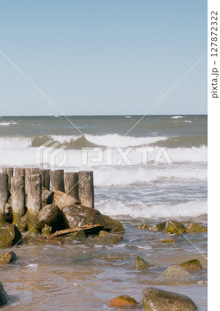 rocky beach with a wooden pier and a pond. The sky is clear and blue. rocky beach with a wooden pier and a pond. The sky is clear and blue. 127872322