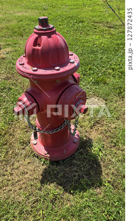 Bright red fire hydrant surrounded by green grass under a sunny sky, showcasing a vital emergency utility for firefighting infrastructure Bright red fire hydrant surrounded by green grass under a sunny sky, showcasing a vital emergency utility for firefighting infrastructure 127872435