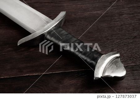 Medieval sword on wooden background. Medieval sword on wooden background. 127873037
