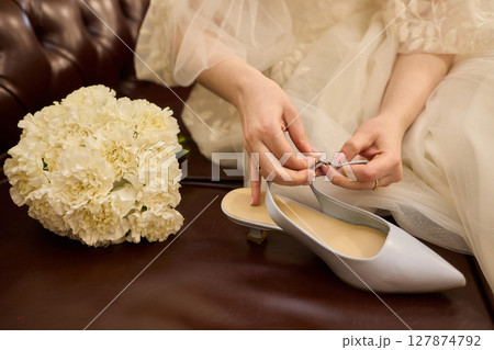 A Romantic Moment The Groom Gently Assists His Bride with Her Beautiful Wedding Shoe 127874792
