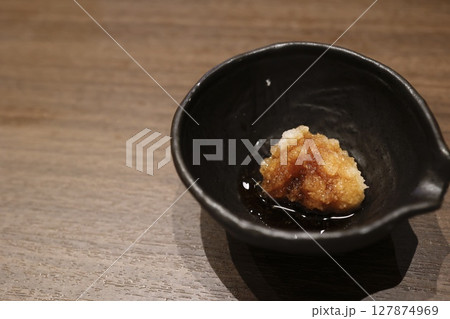 ポン酢をかけた大根おろしの小鉢と木のテーブル ポン酢をかけた大根おろしの小鉢と木のテーブル 127874969